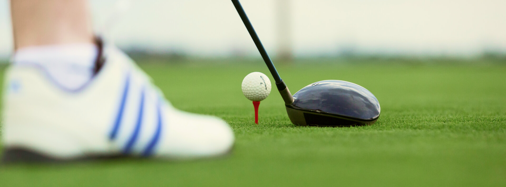 Close da bola de golf sobre a base e taco em posição para fazer a jogada.